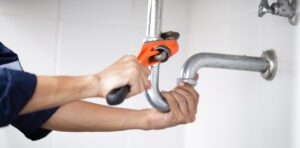 A plumber working in a bathroom dealing with the problem of uric scale in toilet pipes and plumbing.