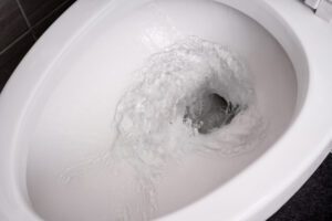 A sanitary napkin being flushed down the toilet. 